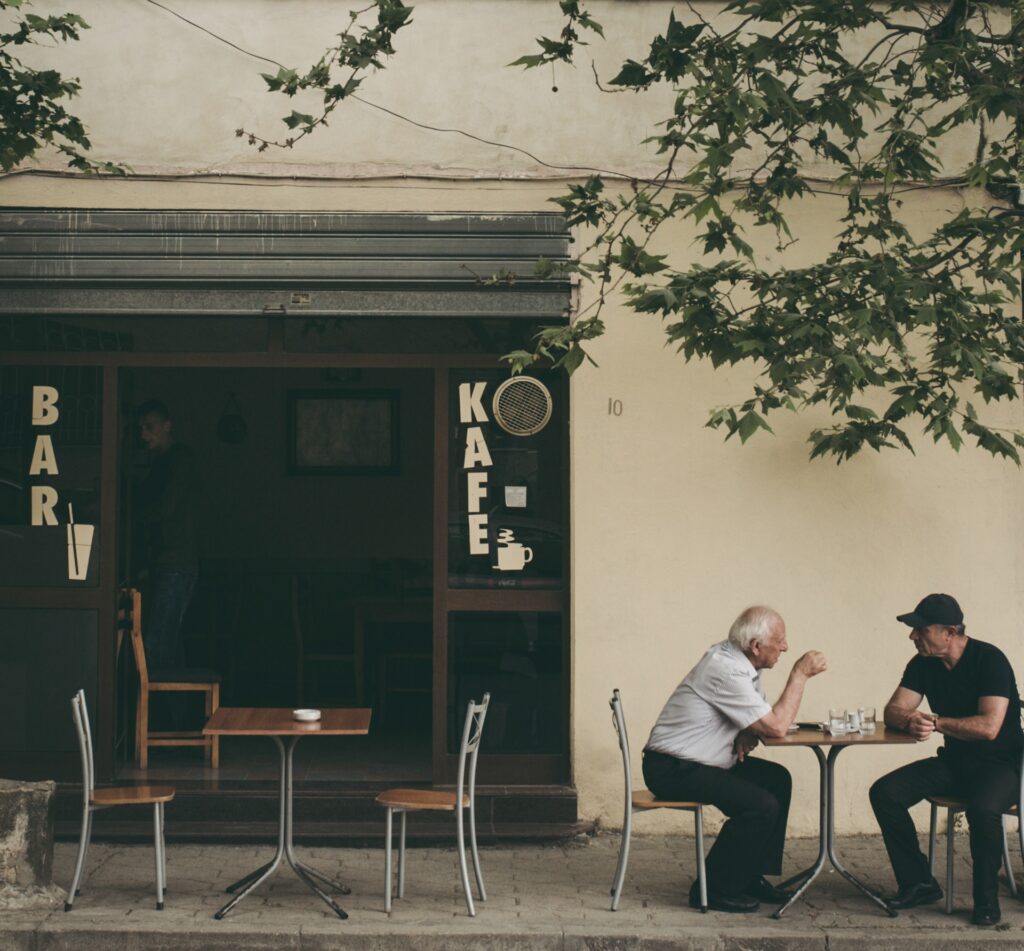 Two men chatting outside a cafe - Photo by Juri Gianfrancesco on Unsplash
